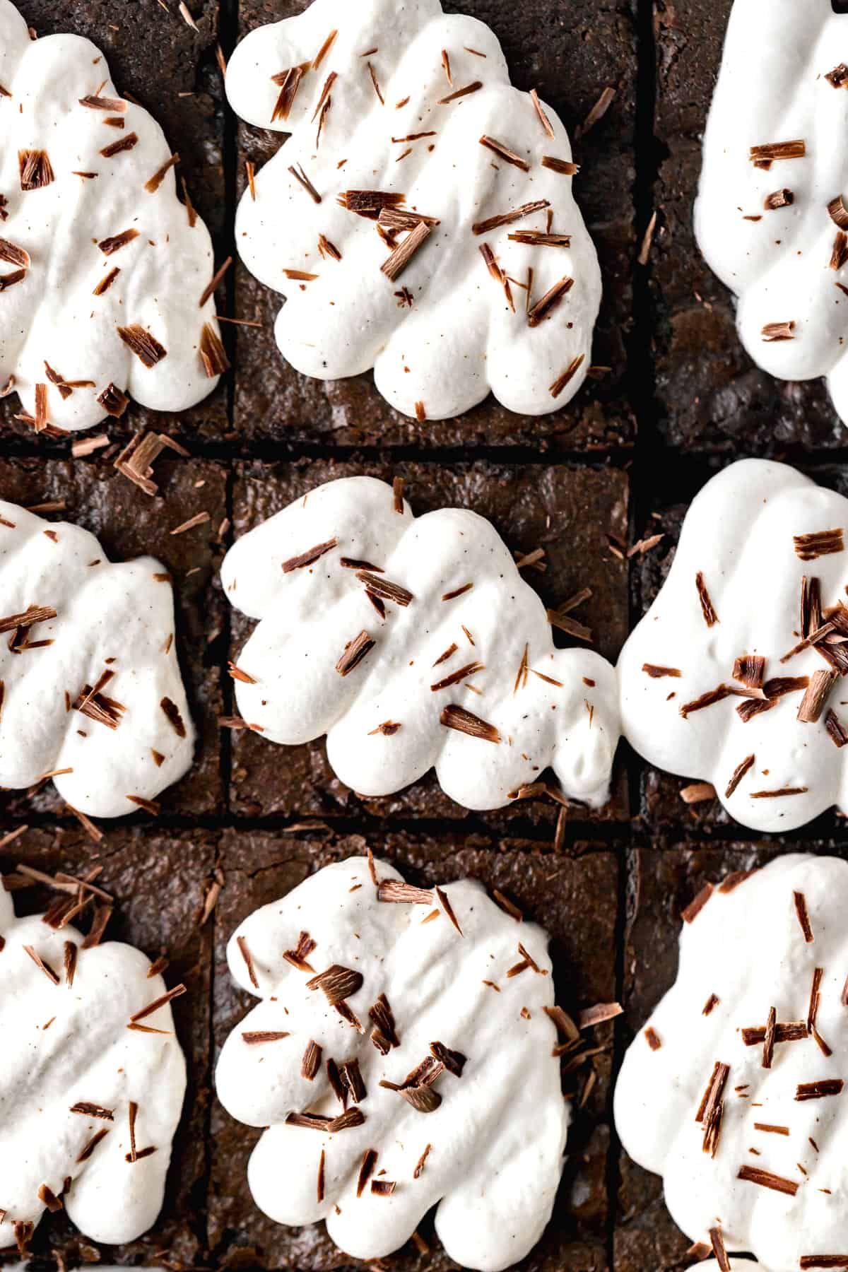 close up of cherry brownies with whipped cream and shaved chocolate.