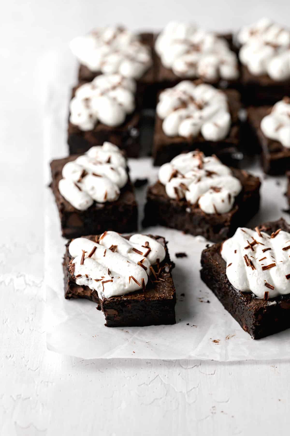 black forest brownies with whipped cream spaced out on parchment paper.