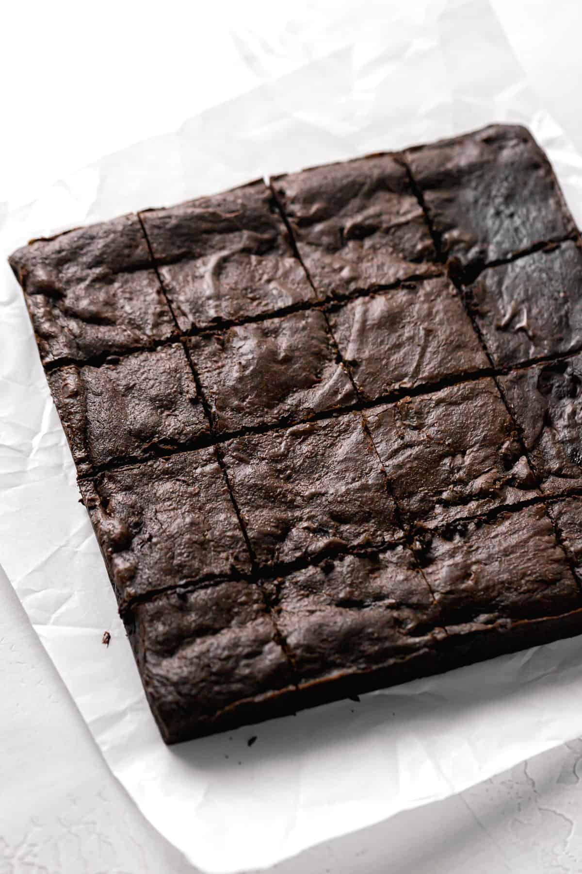 baked brownies cut into 16 squares on parchment paper