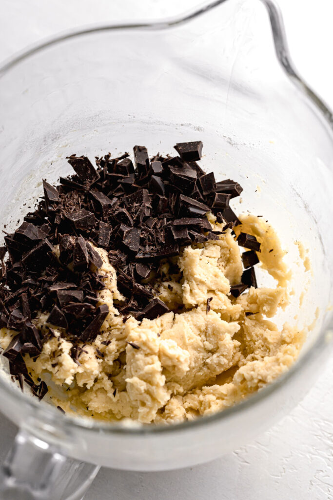 chocolate added to cookie dough in glass bowl