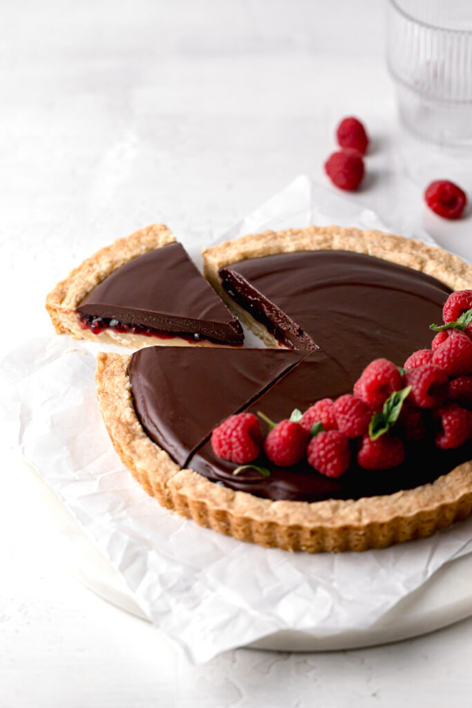 slice pulled away from chocolate raspberry tart to show layers