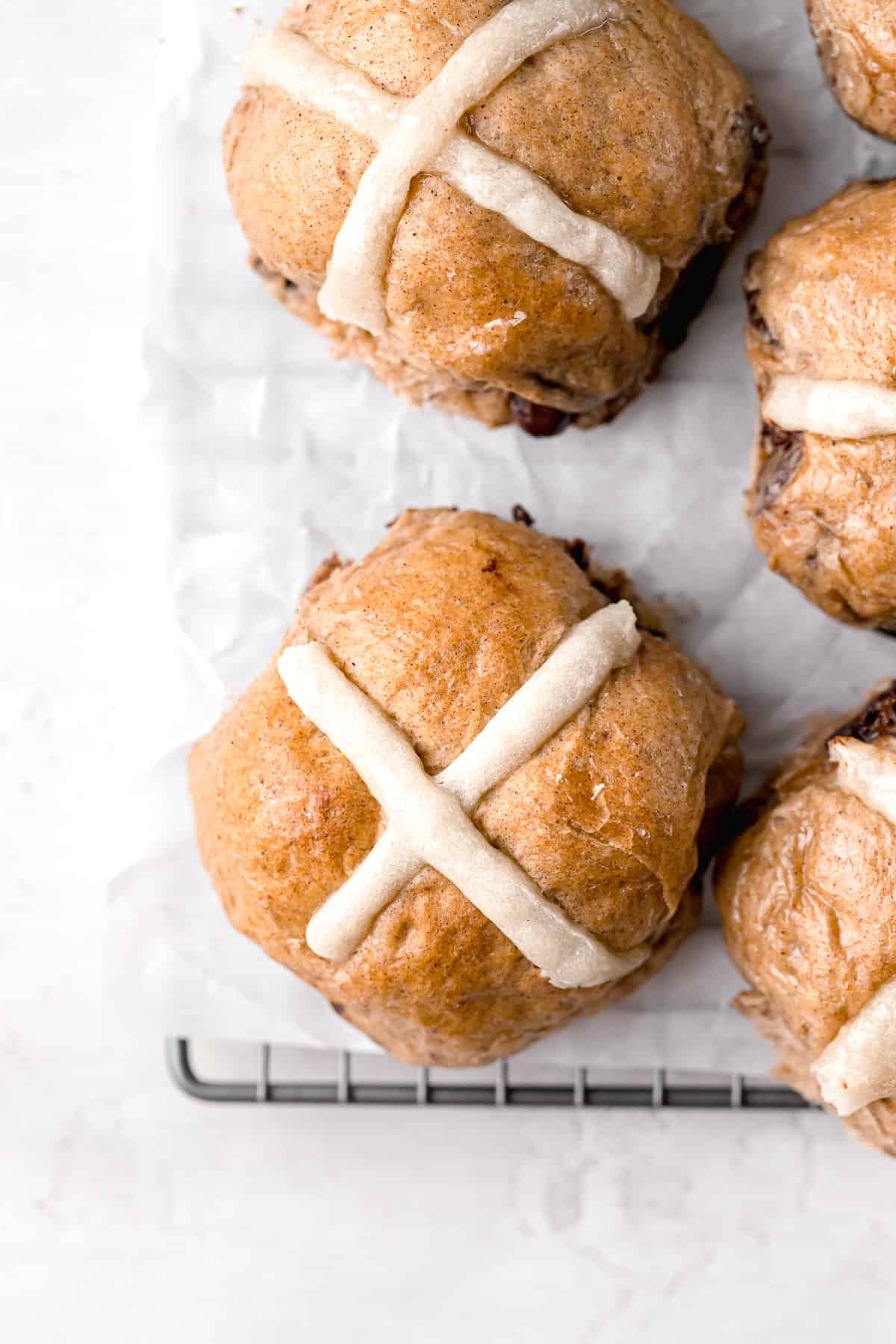 hot cross buns on parchment lined wire rack.