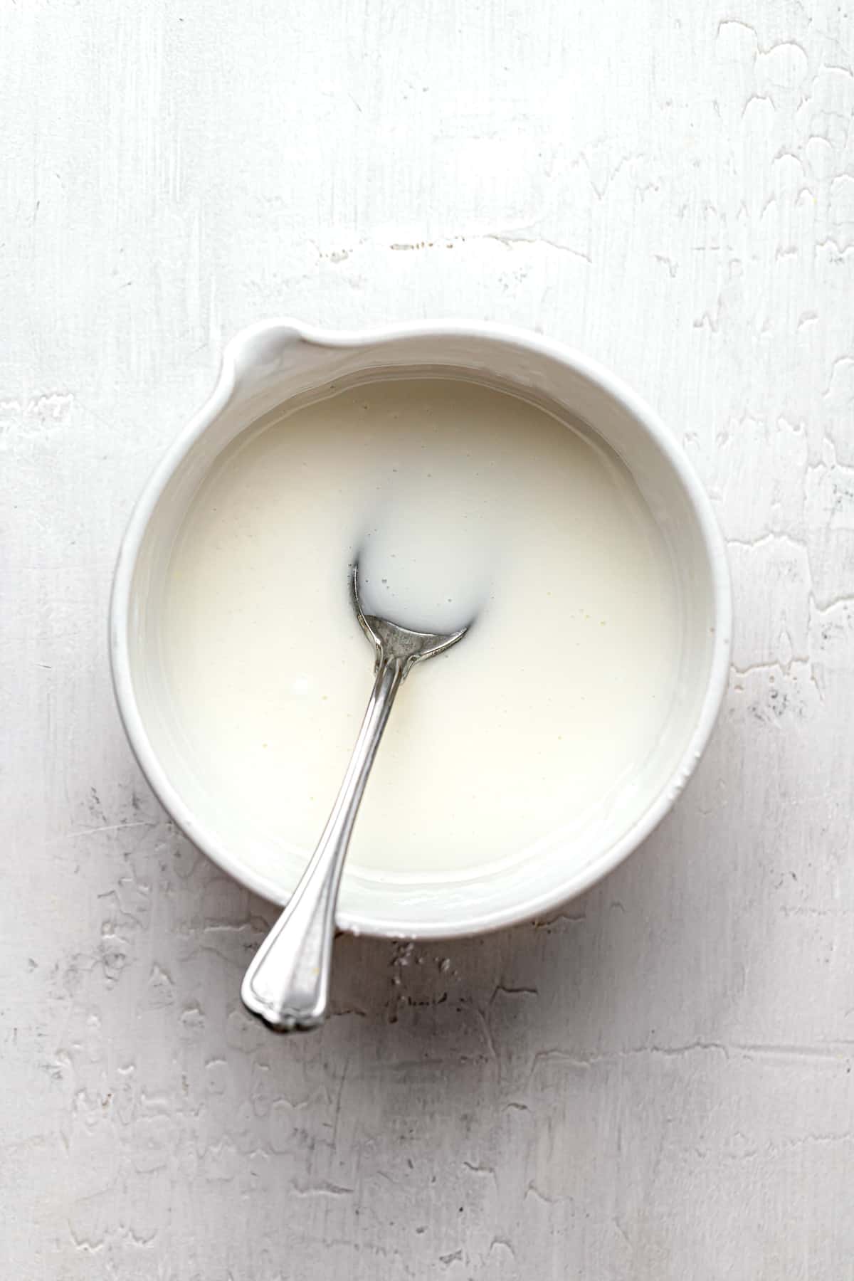 lemon glaze in white bowl with spoon.