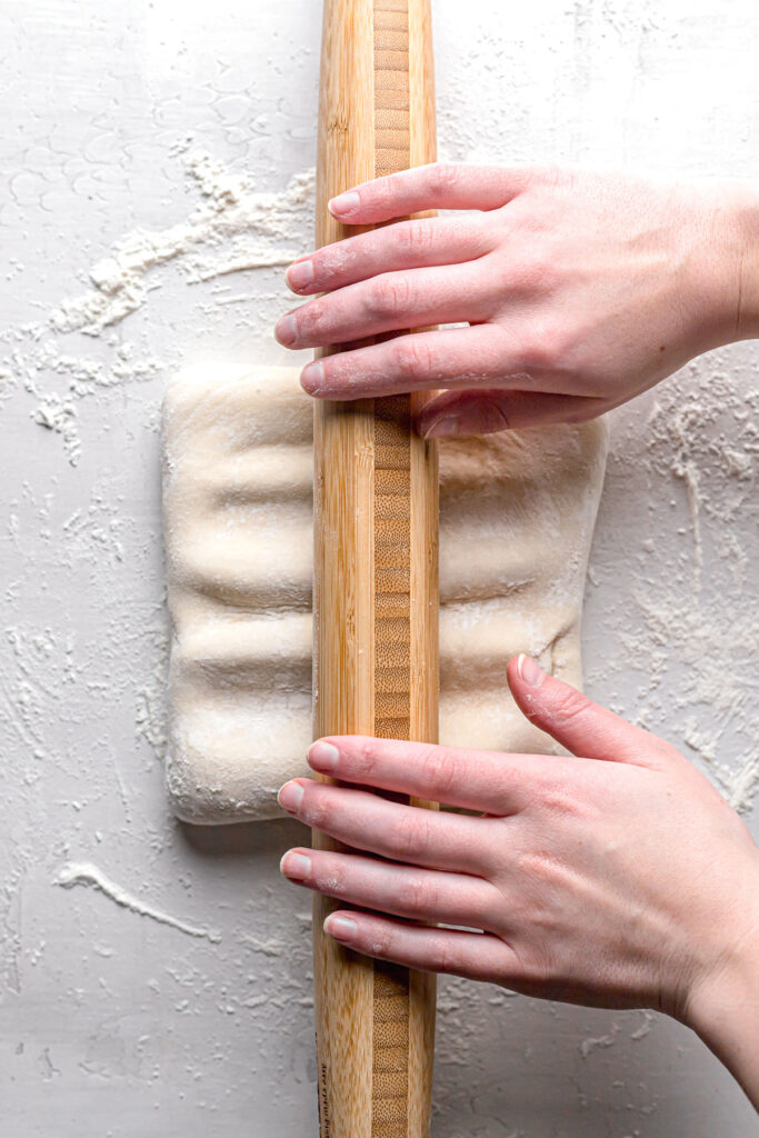 using rolling pin to press indentations in dough 