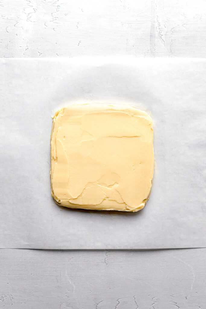 butter block shaped into square on parchment paper