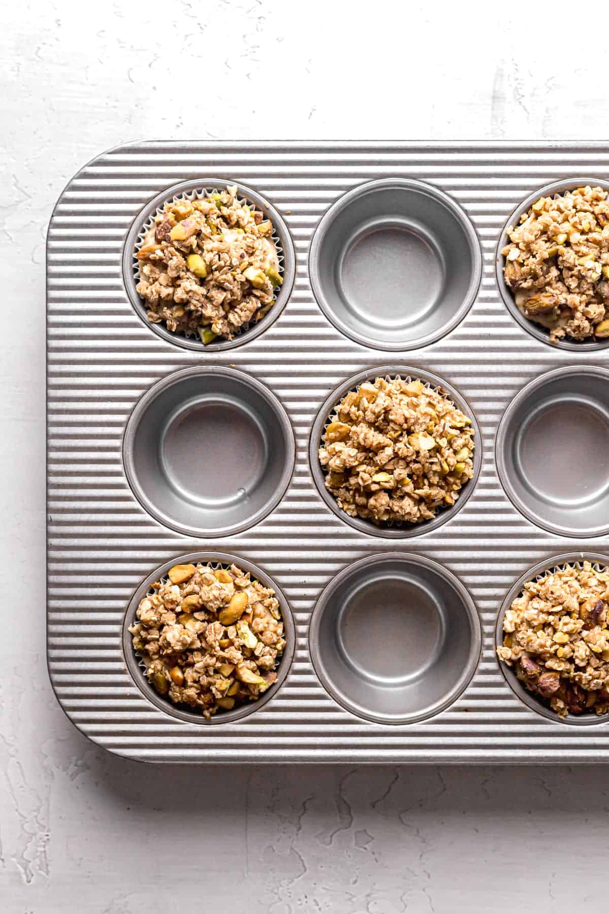 muffin batter with oat streusel on top in muffin pan.