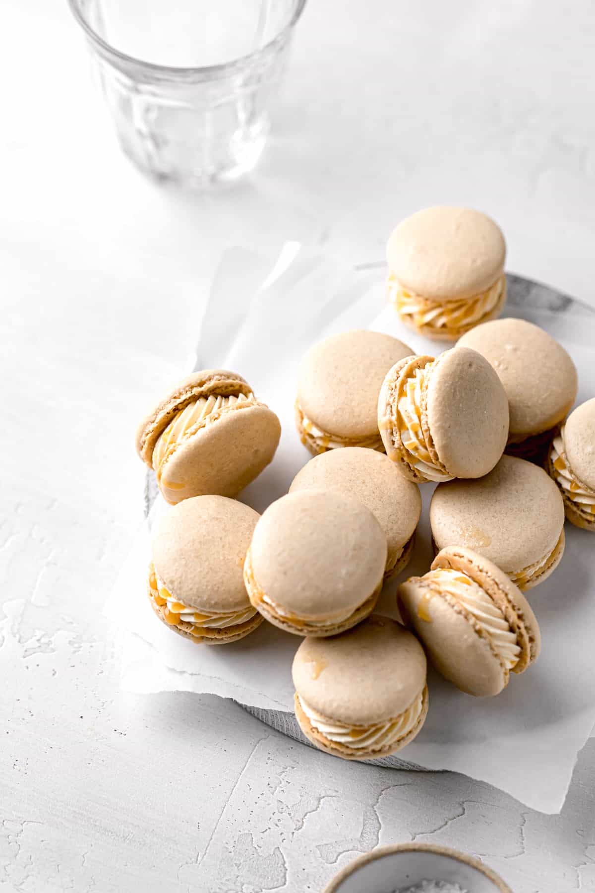 salted caramel macarons piled on parchment lined wooden board