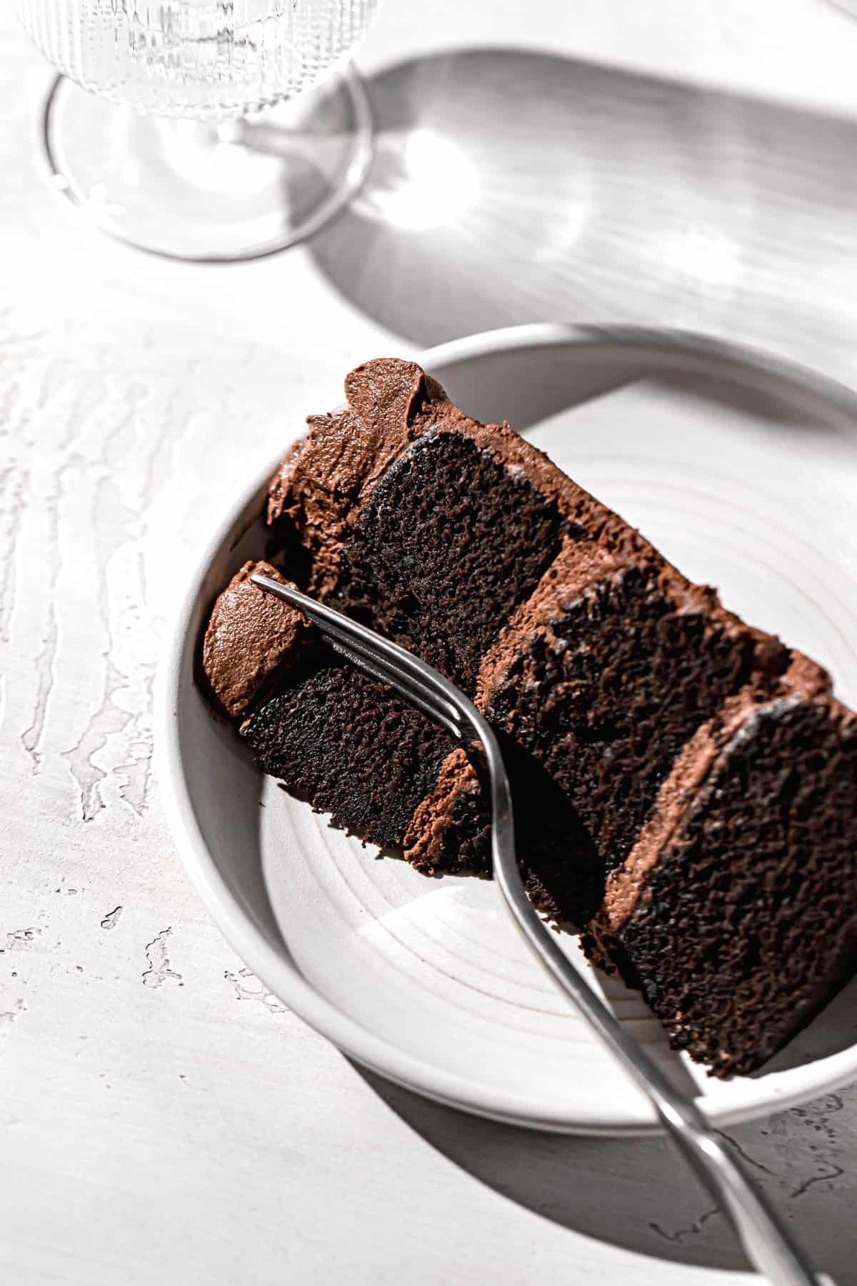 slice of dairy free chocolate cake on white plate with fork.