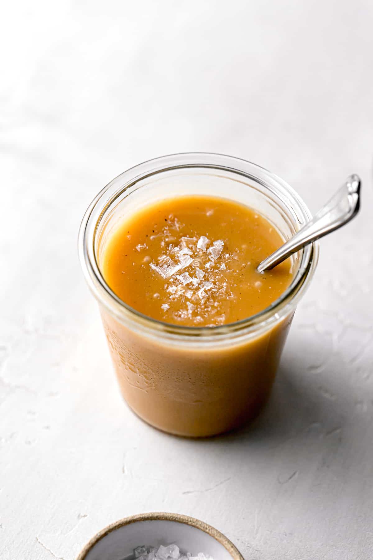 foolproof salted caramel sauce in glass weck jar with a pinch of flaky sea salt added on top.