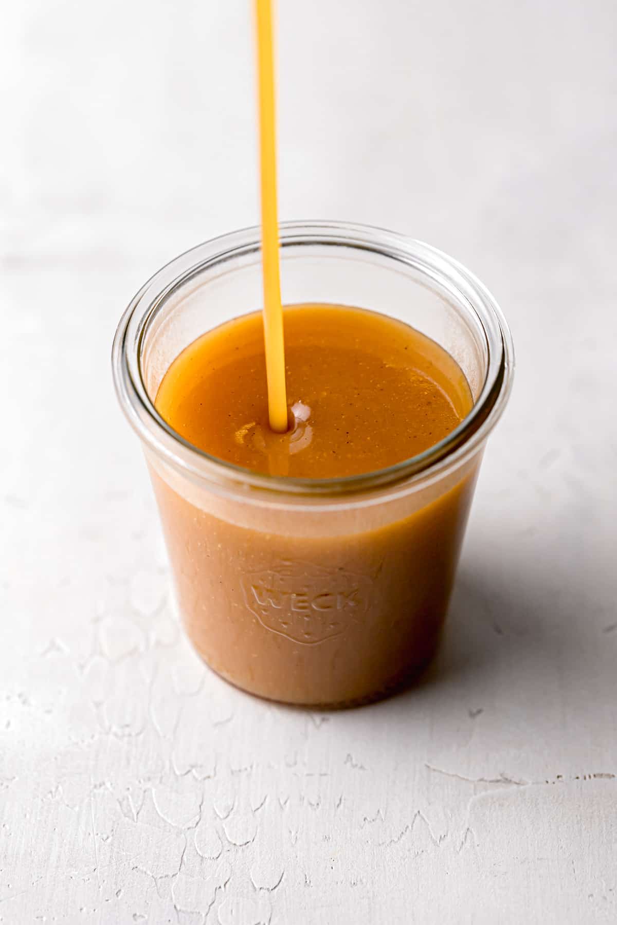 foolproof salted caramel sauce being poured into small glass weck jar.