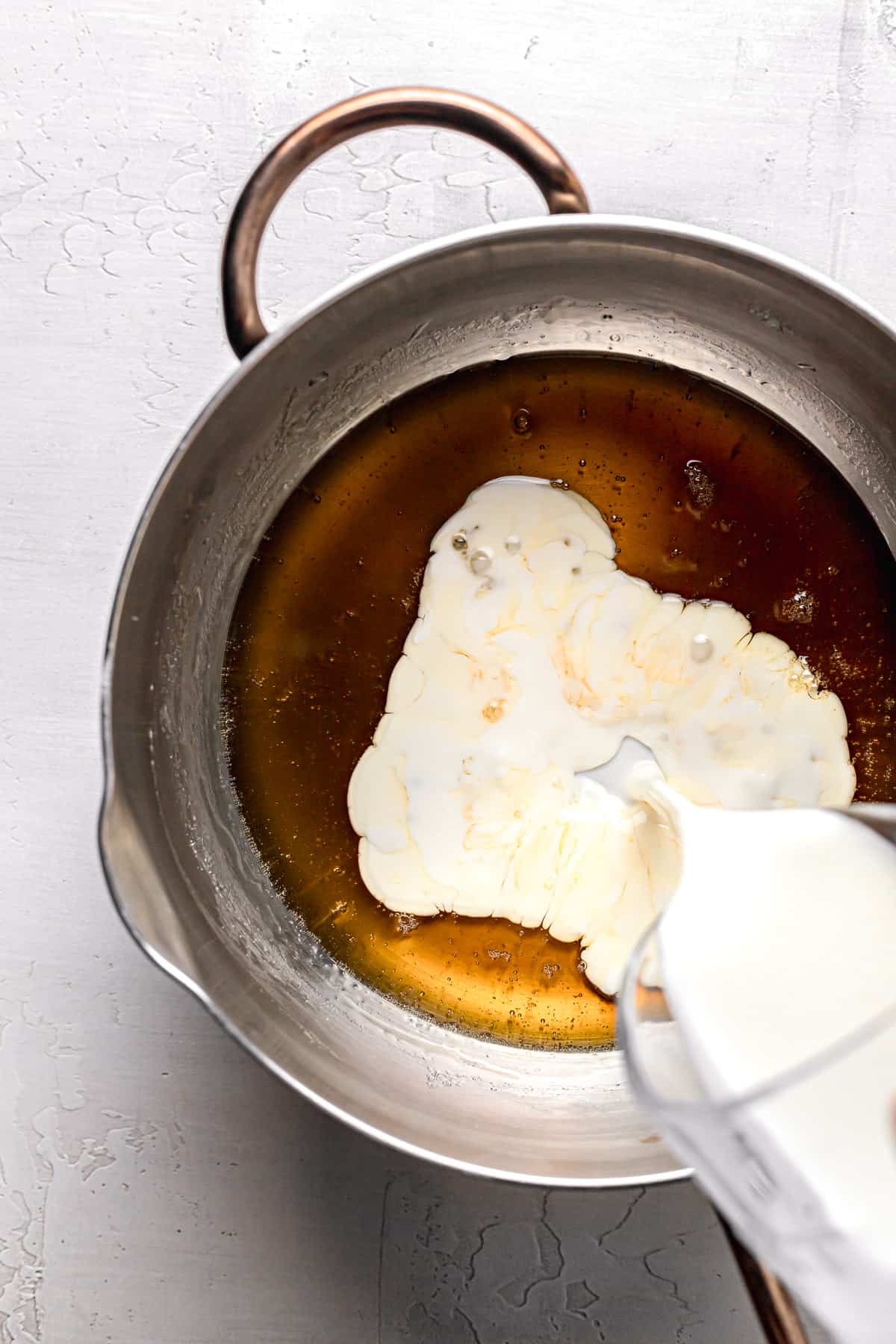 heavy cream being poured into caramel.