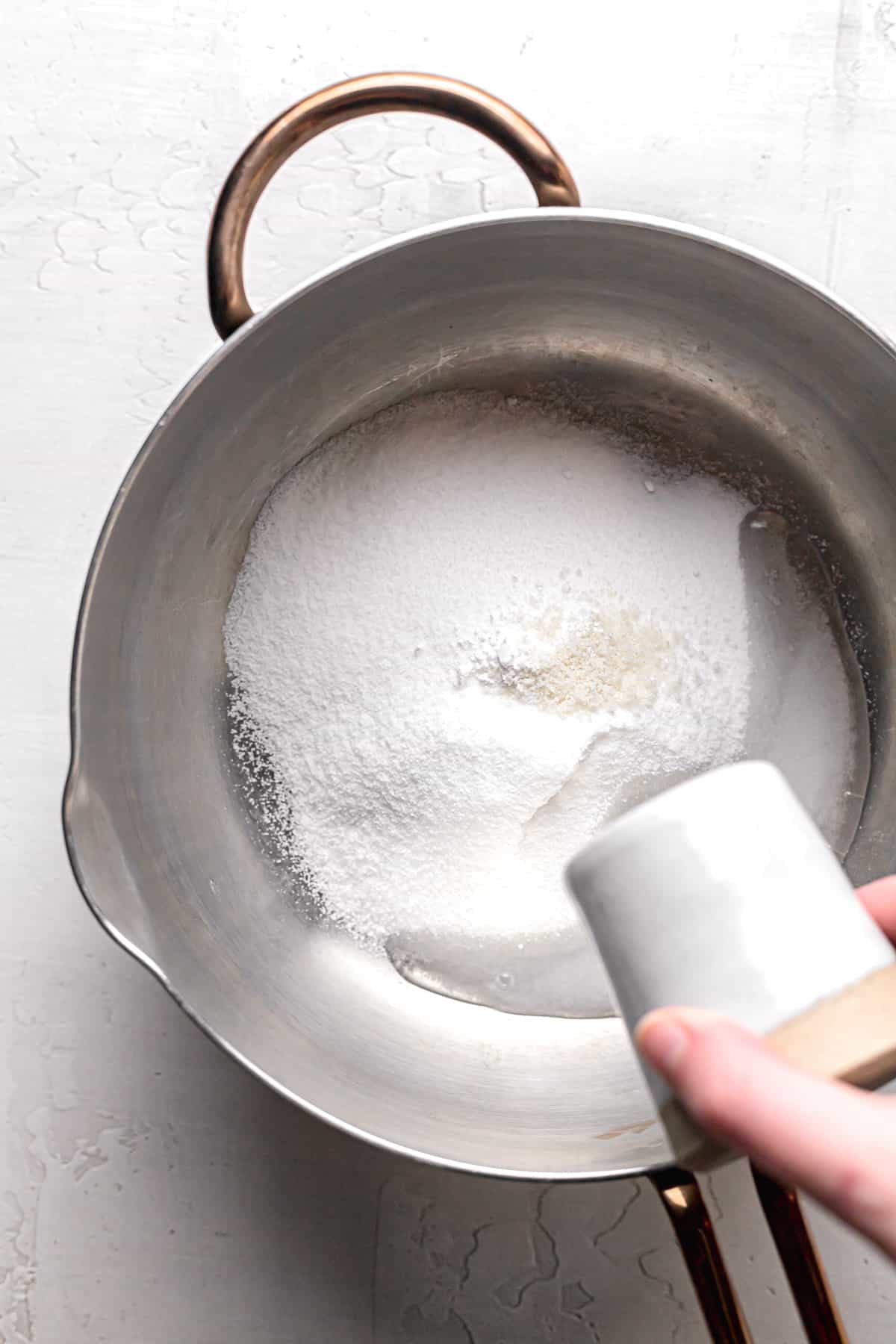 water being poured over sugar in saucepan.