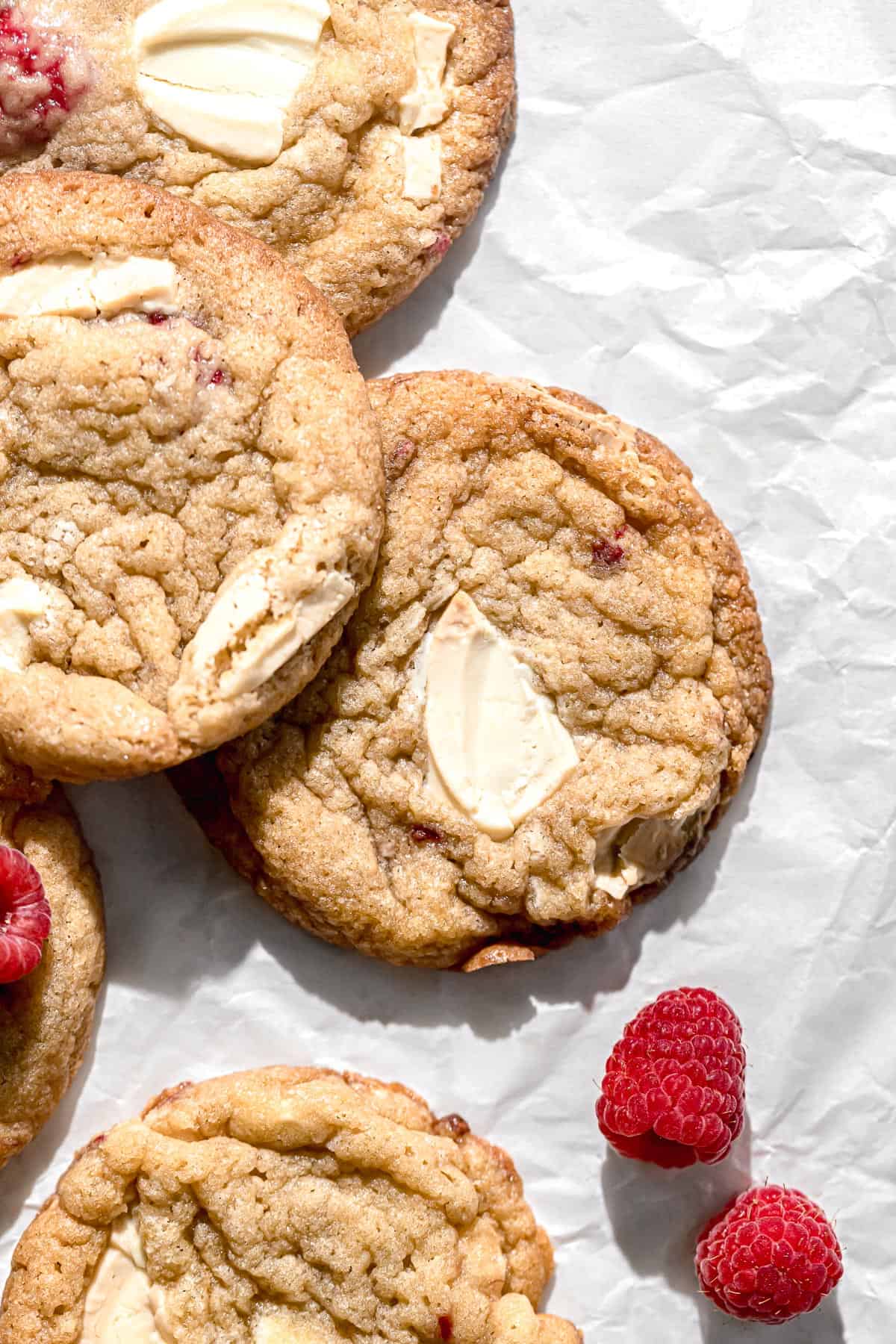 raspberry white chocolate cookies piled on parchment paper.