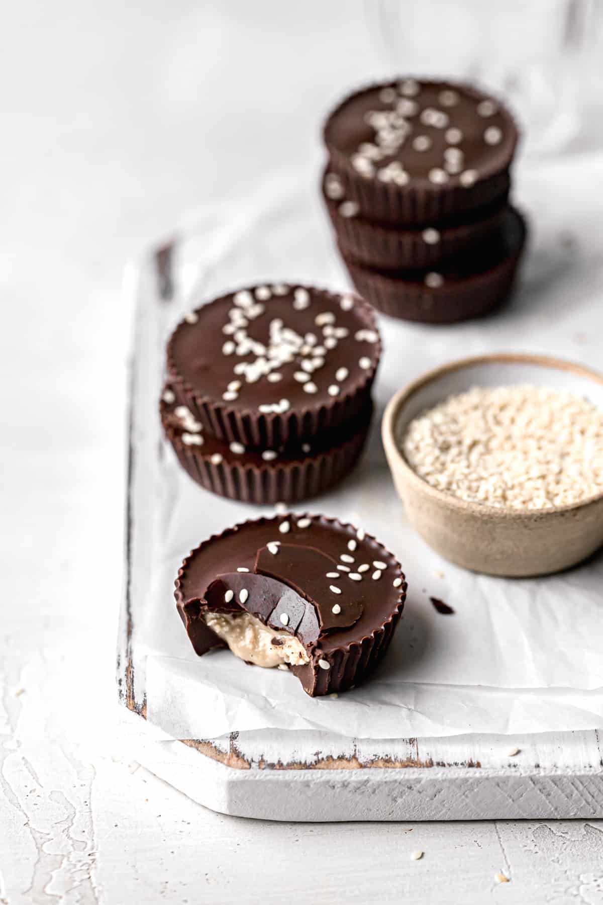 dark chocolate tahini cups on parchment lined wooden board.