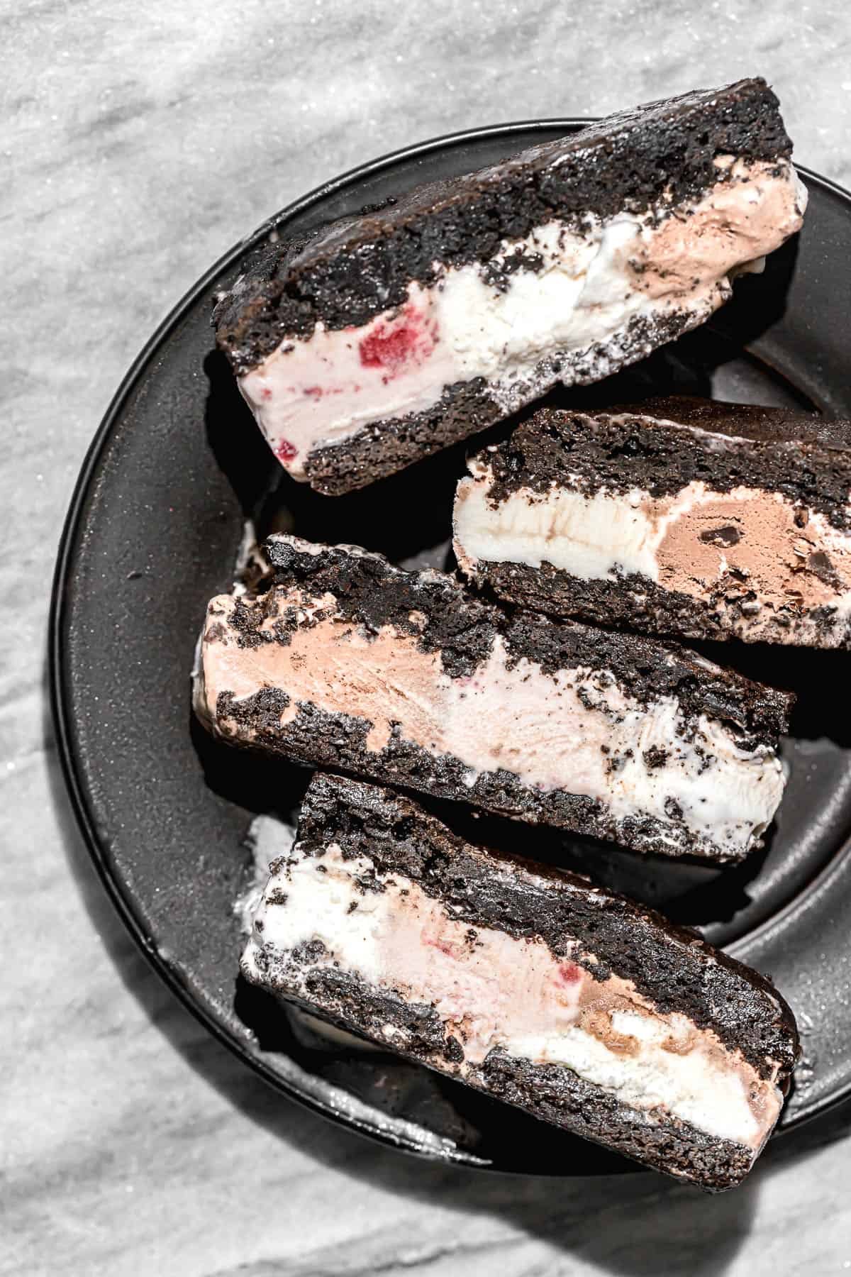 gluten free brownie ice cream sandwiches on black plate.