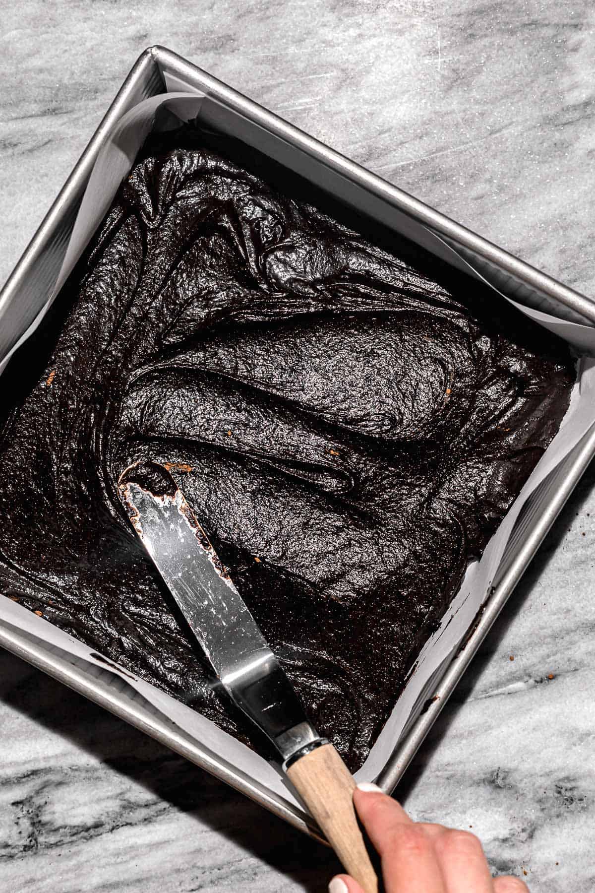 gluten free brownie batter being spread into square pan.