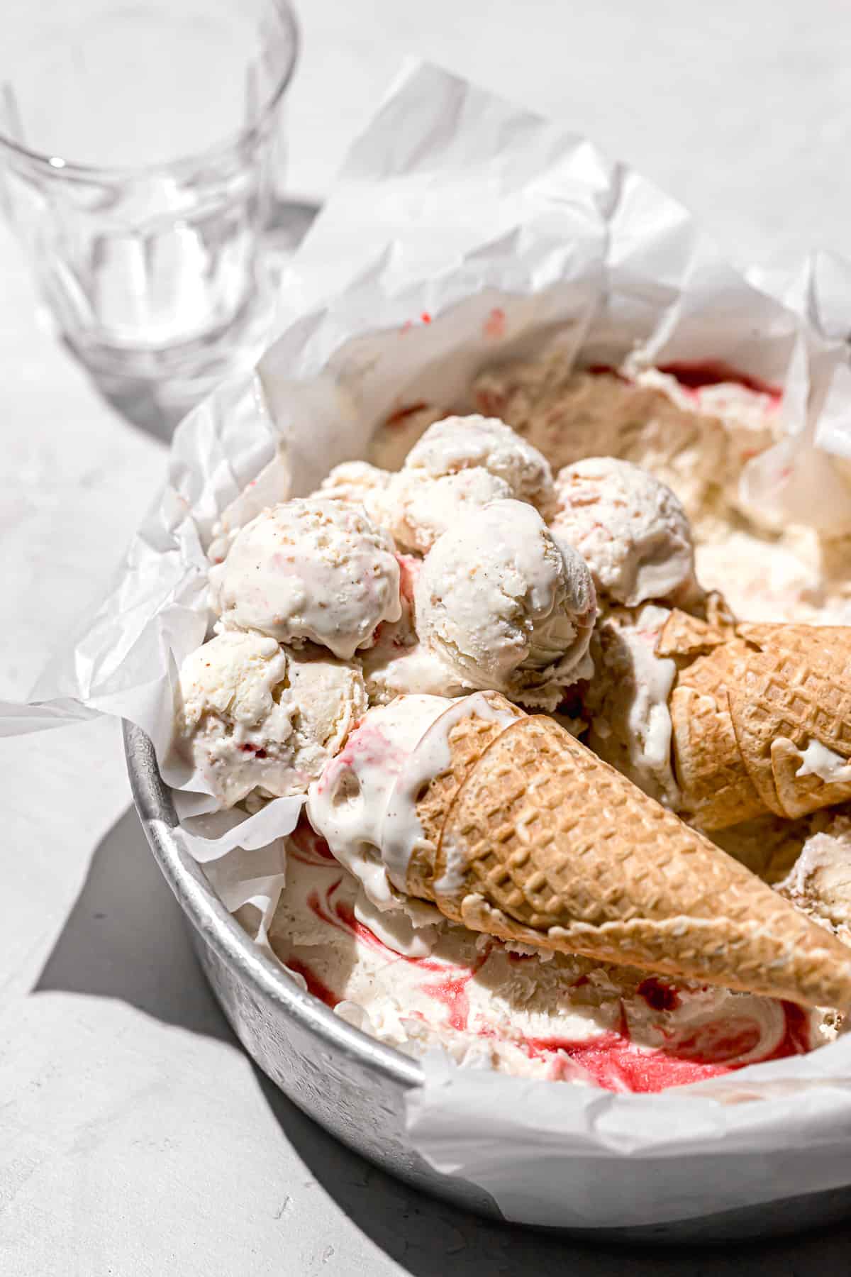strawberry cheesecake ice cream in round pan with two waffle cones