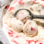 three scoops of strawberry cheesecake ice cream with ice cream scoop