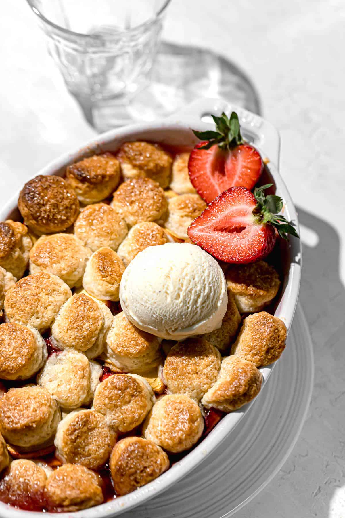 strawberry peach cobbler with vanilla ice cream and fresh strawberries.