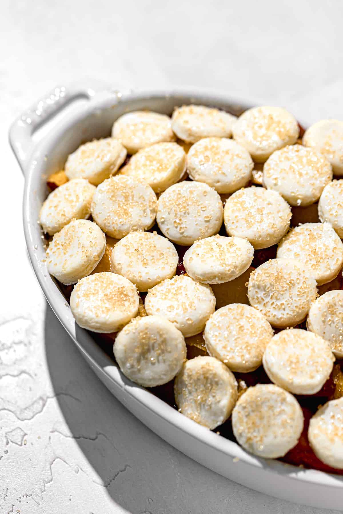 cream biscuits lined up on top of filling in oval dish.