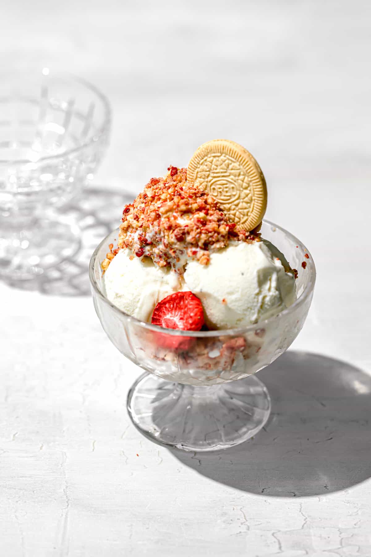 vanilla ice cream topped with strawberry shortcake crumble in glass bowl