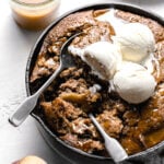 caramel apple dump cake with ice cream and two spoons dug into it