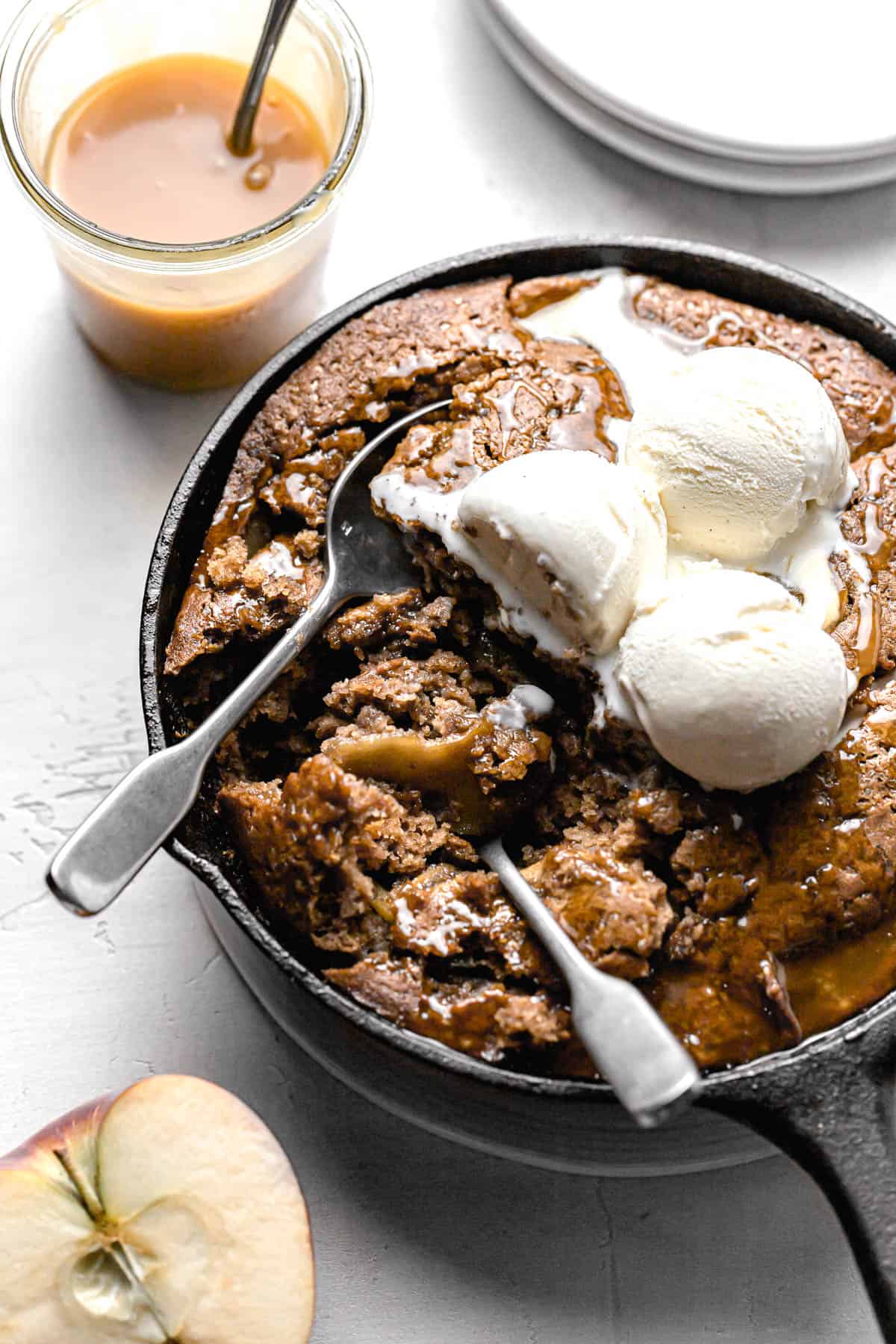 caramel apple dump cake with ice cream and two spoons dug into it.