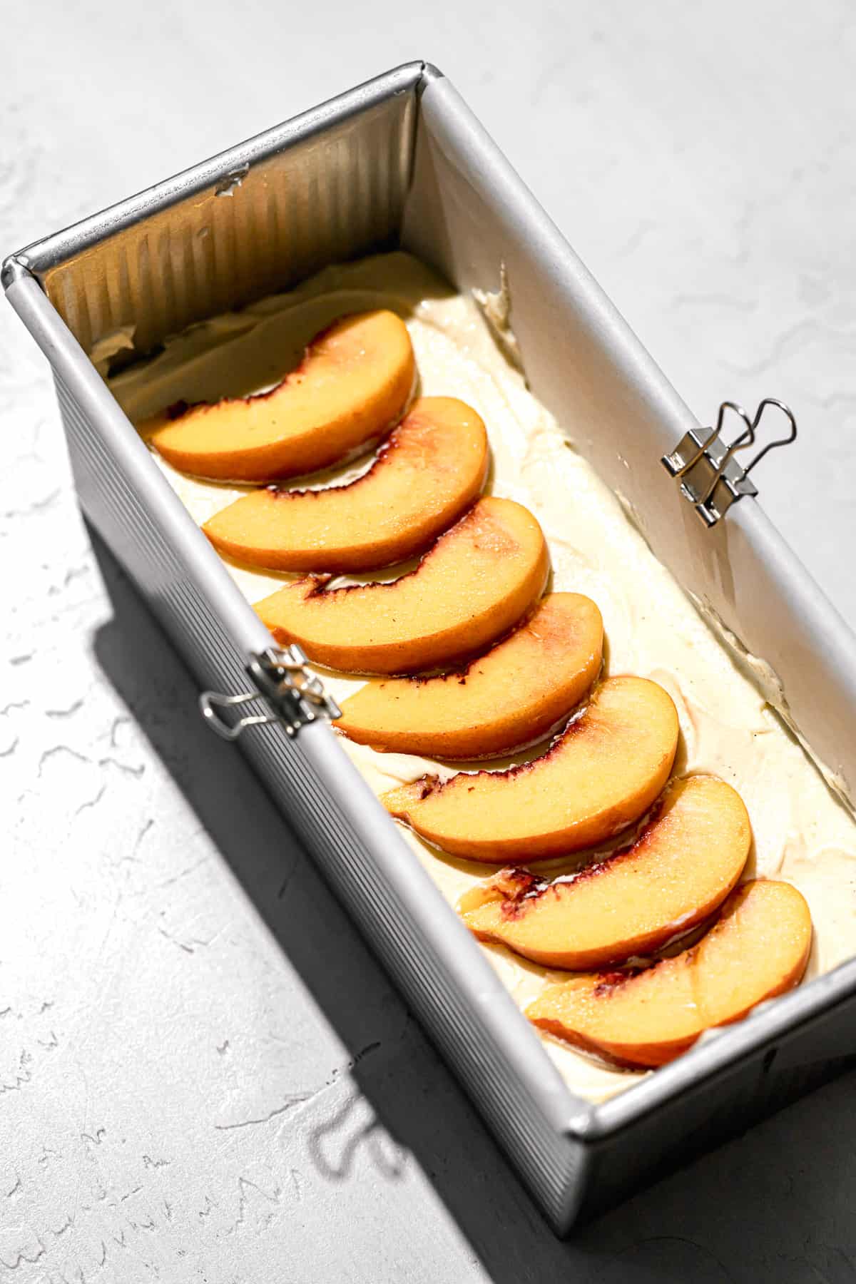 batter in pan with peaches on top.