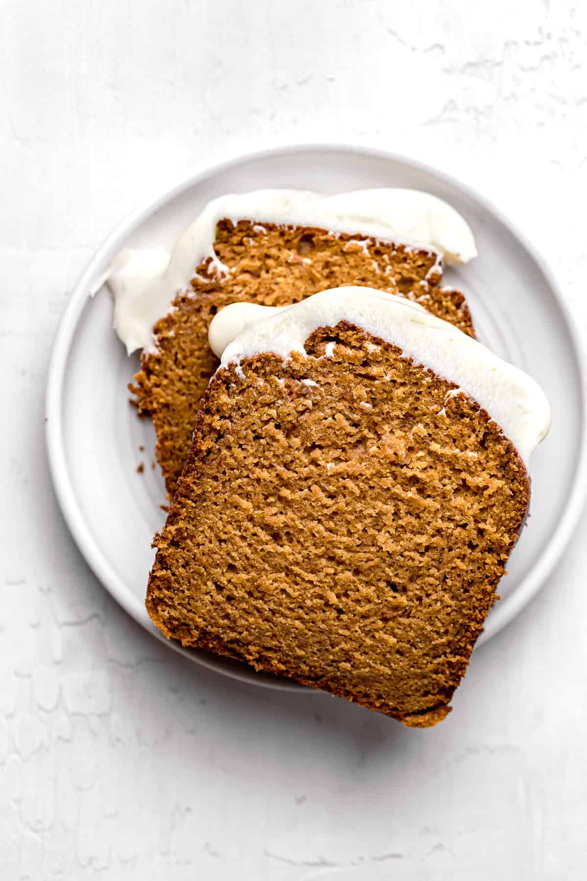 pumpkin bread with cream cheese frosting slices on white plate.