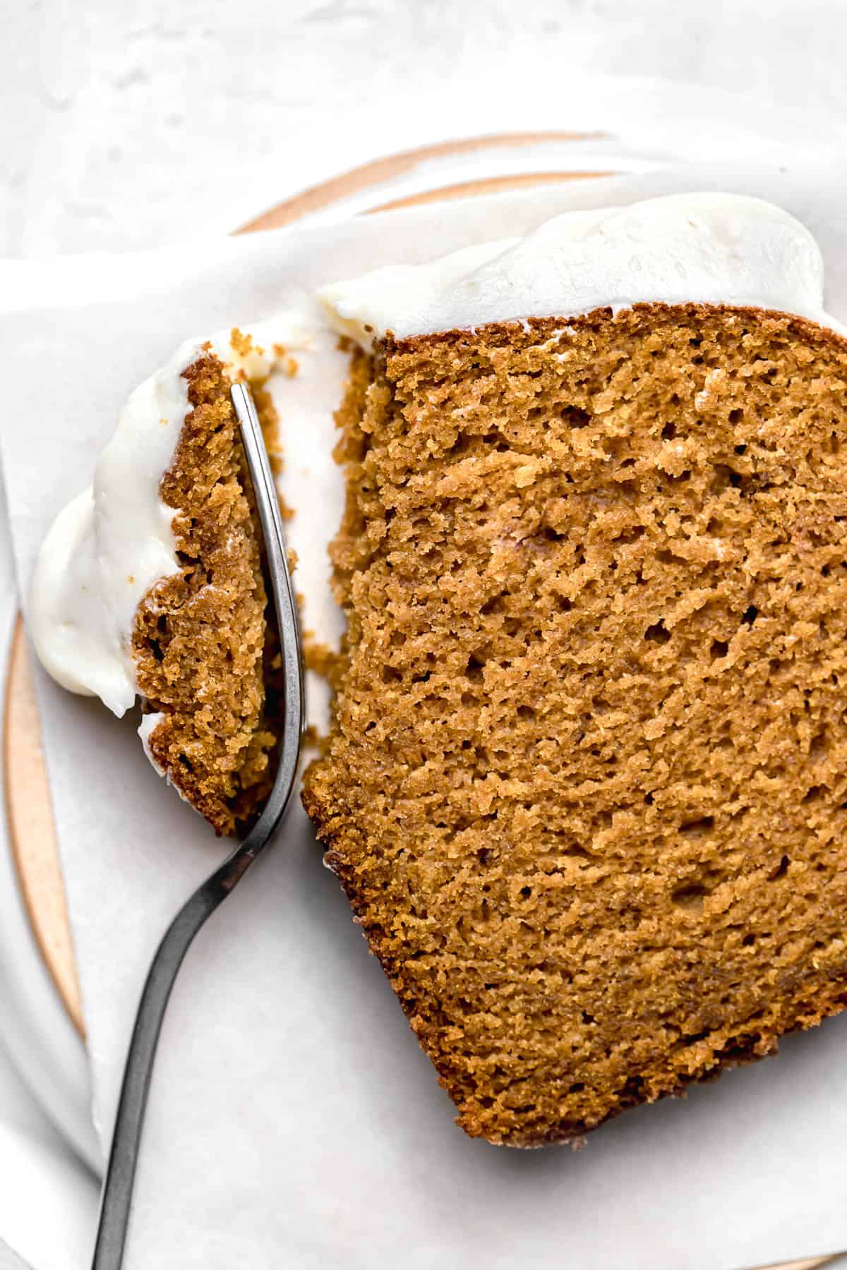 one piece of moist pumpkin bread on parchment paper with fork.