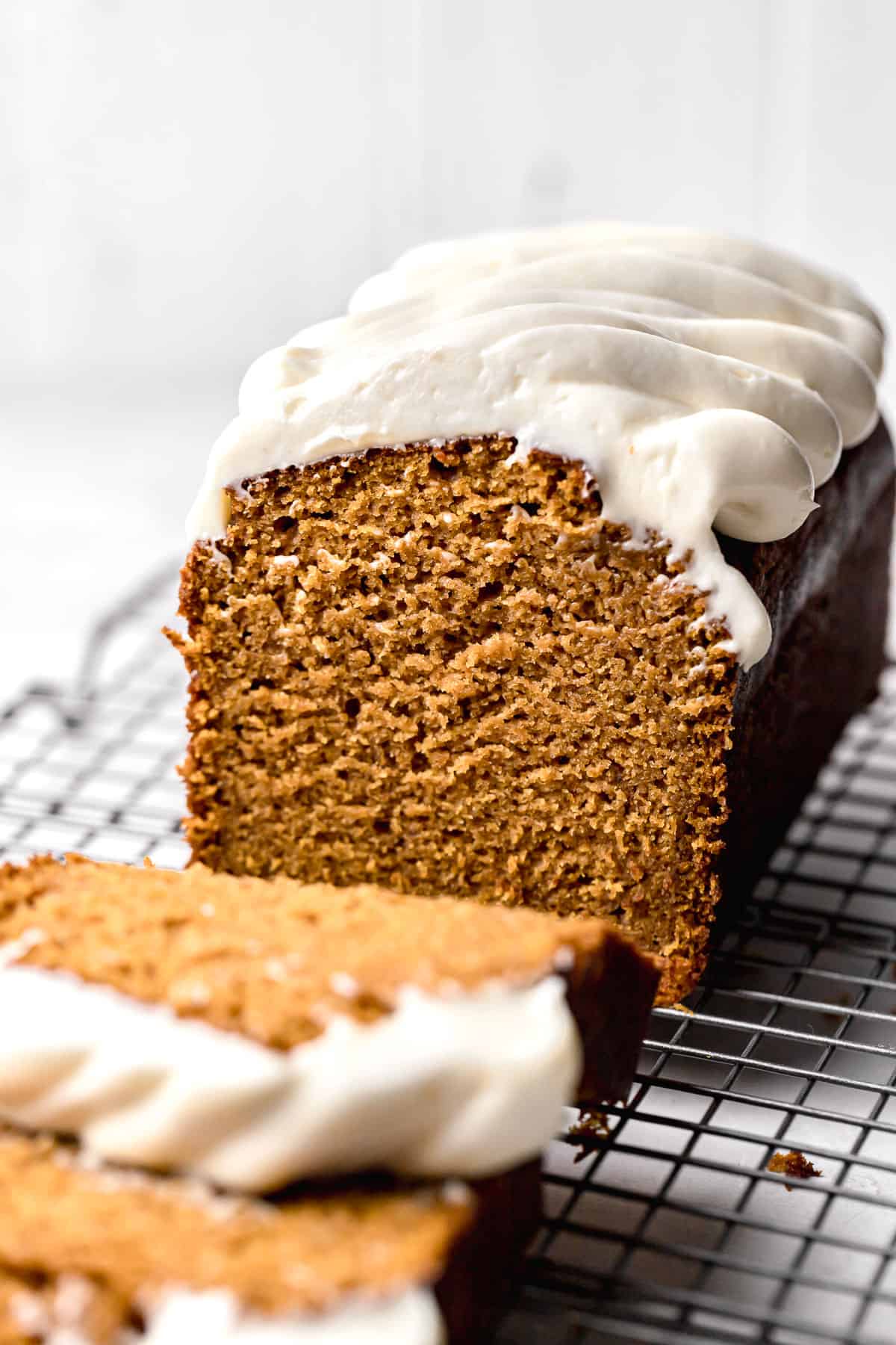 cut pumpkin bread with cream cheese frosting on wire rack.