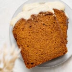 two slices of pumpkin bread with cream cheese frosting on small plate.