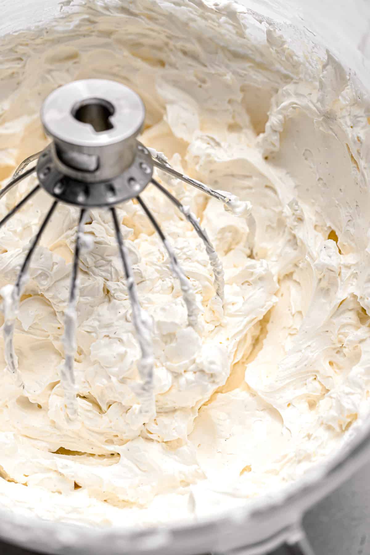 swiss meringue buttercream with whisk attachment in glass bowl.