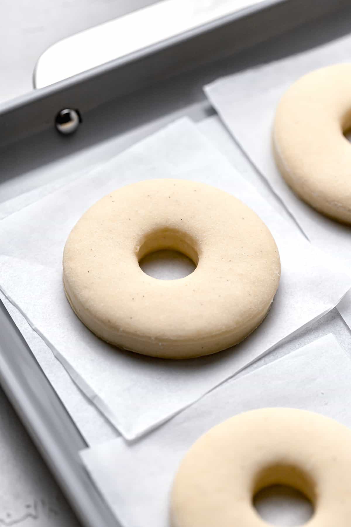 brioche dough cut out into donuts on individual parchment squares.