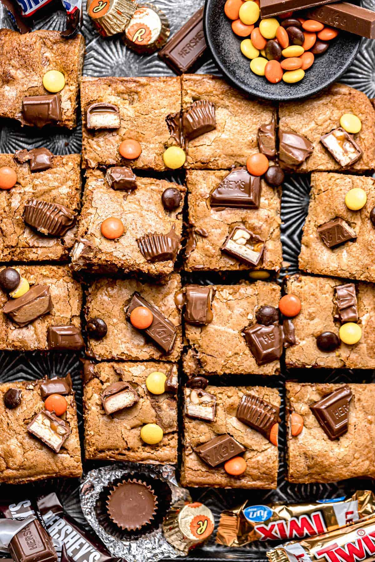 candy bar blondies cut into 16 squares on black tray.