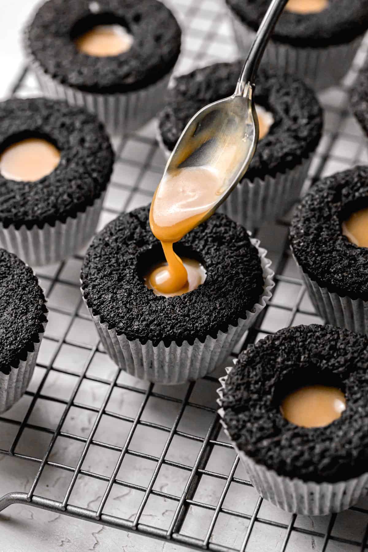 black cocoa cupcakes being filled with caramel sauce.