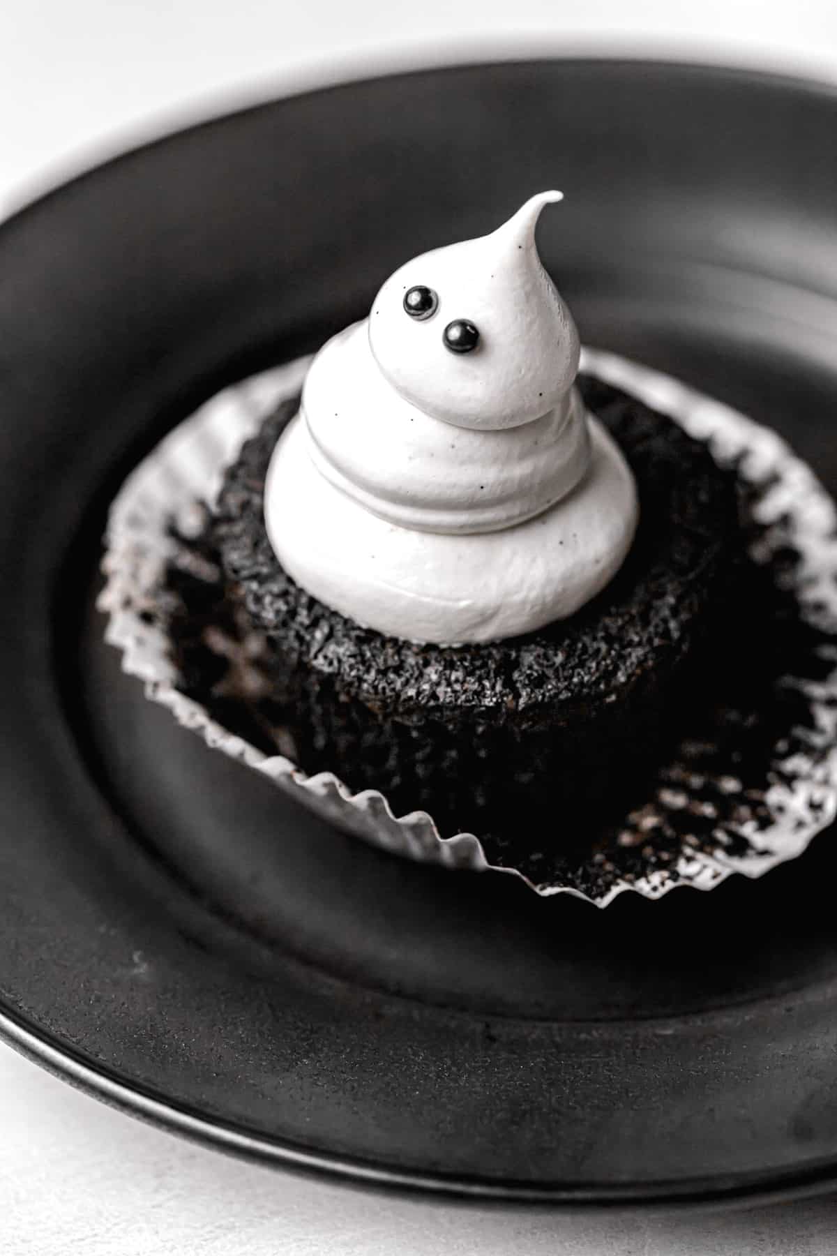 one chocolate caramel cupcake on black plate.