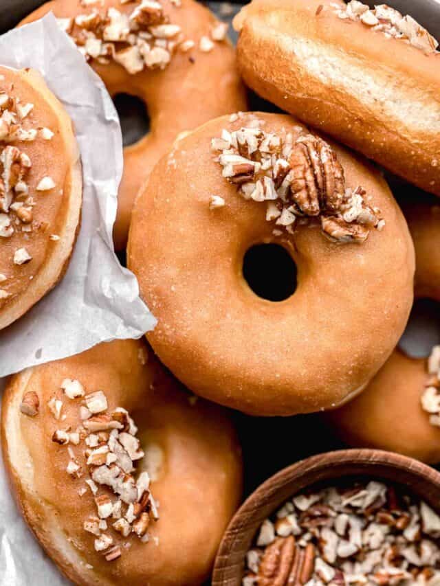 maple donuts with pecans piled on black tray