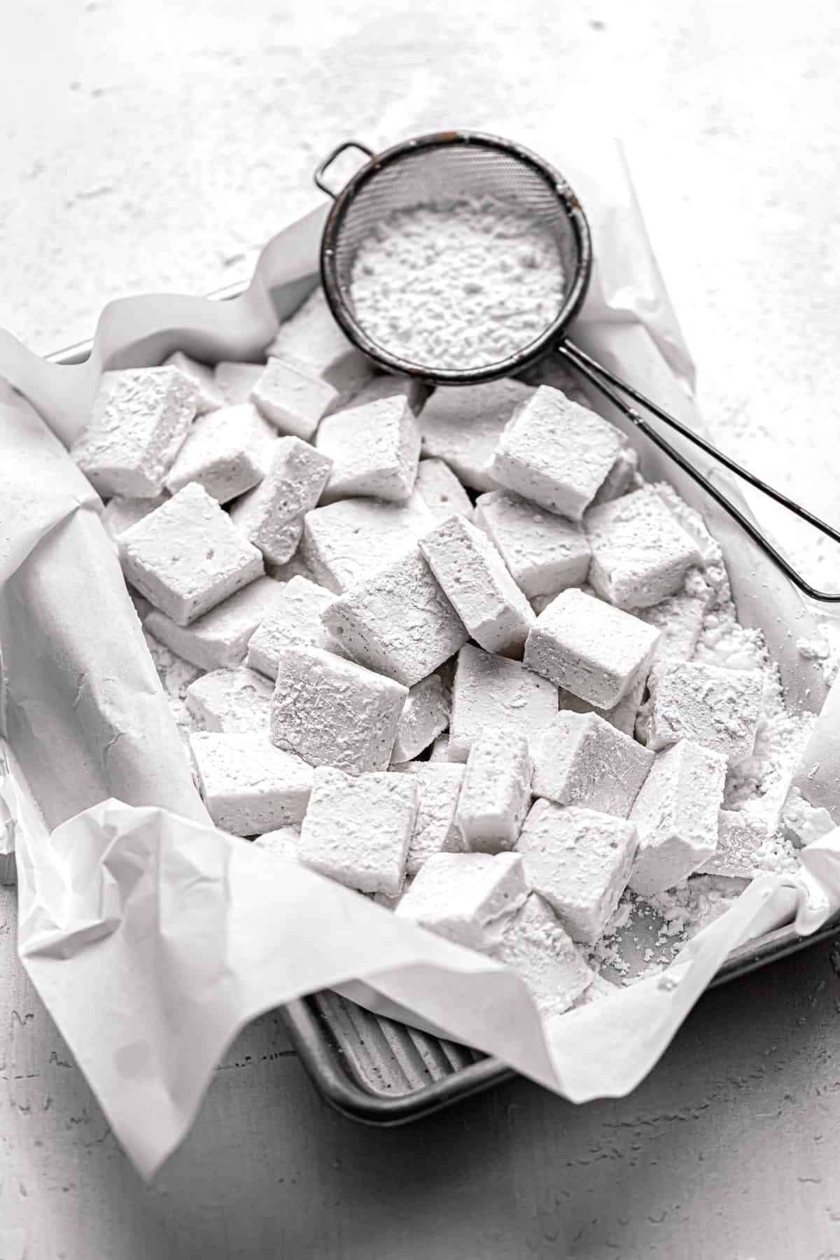 homemade marshmallows in a parchment lined tray.