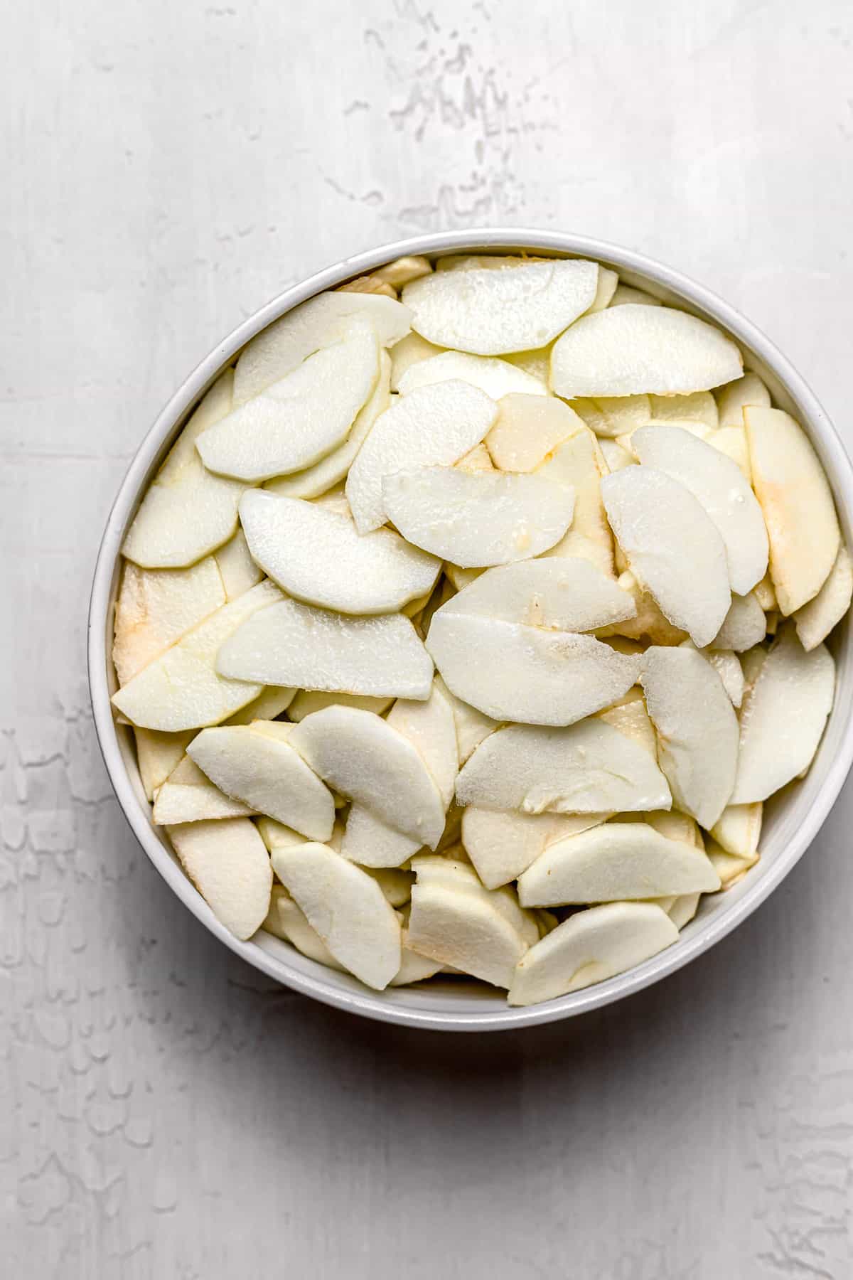 sliced apples in white bowl.