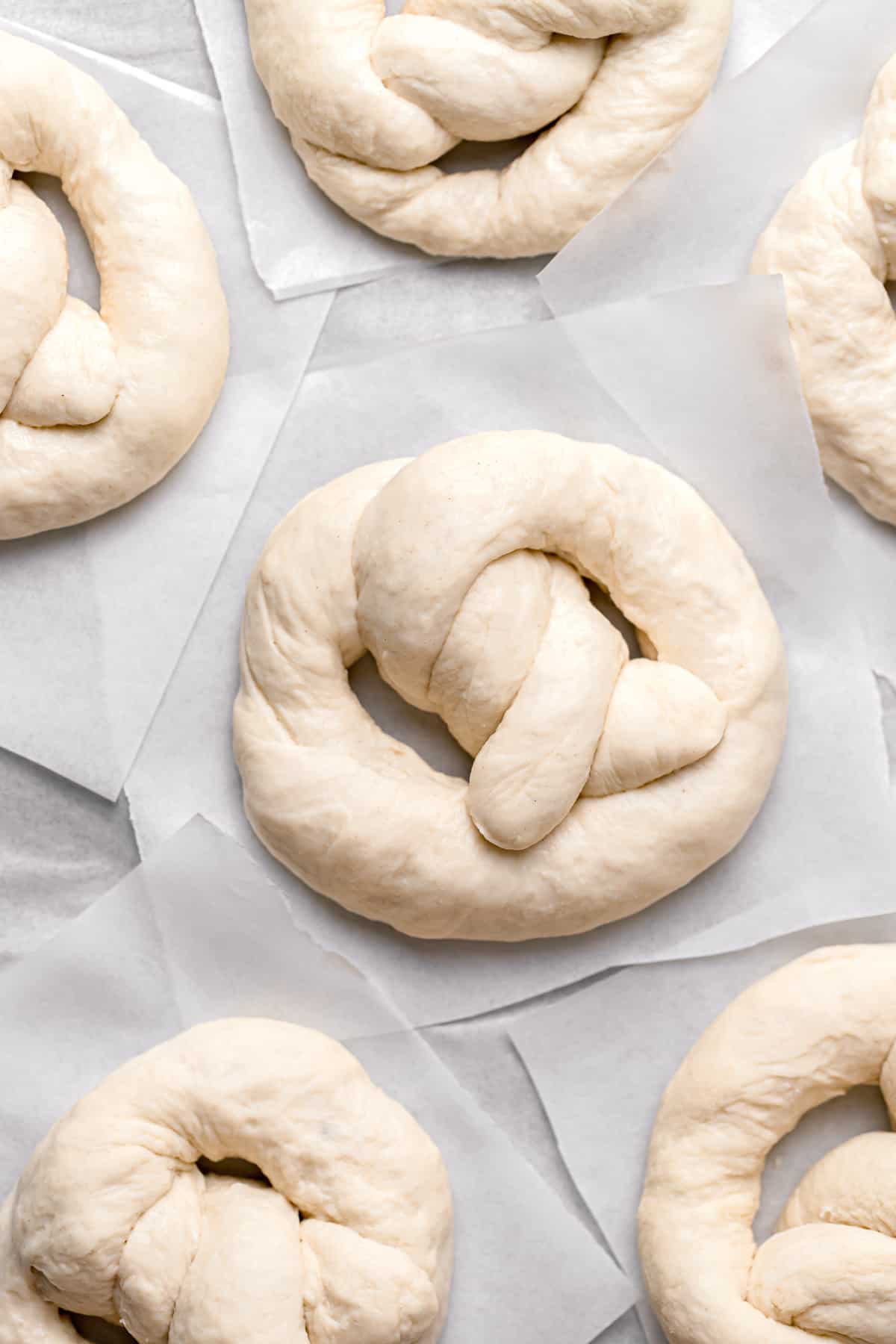 shaped soft pretzels on a baking sheet with parchment paper.