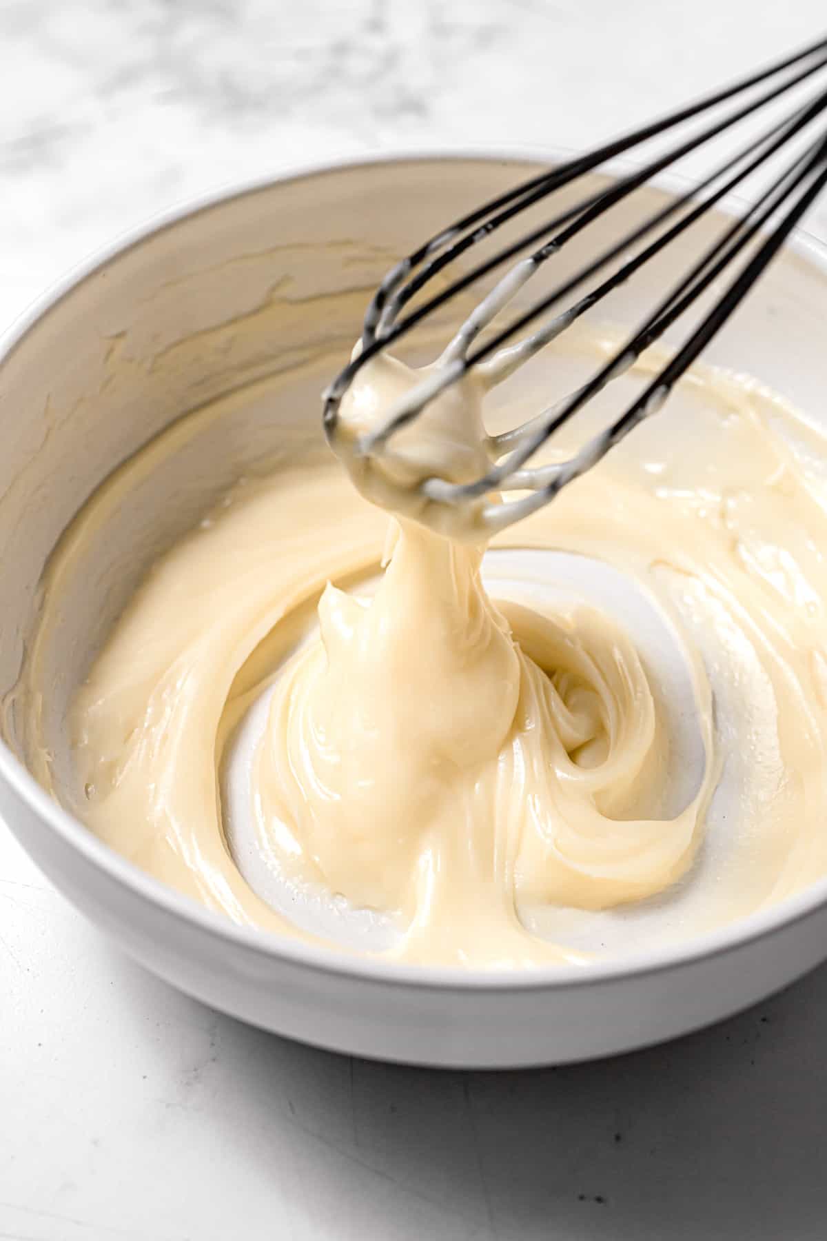 cream cheese icing in white bowl.