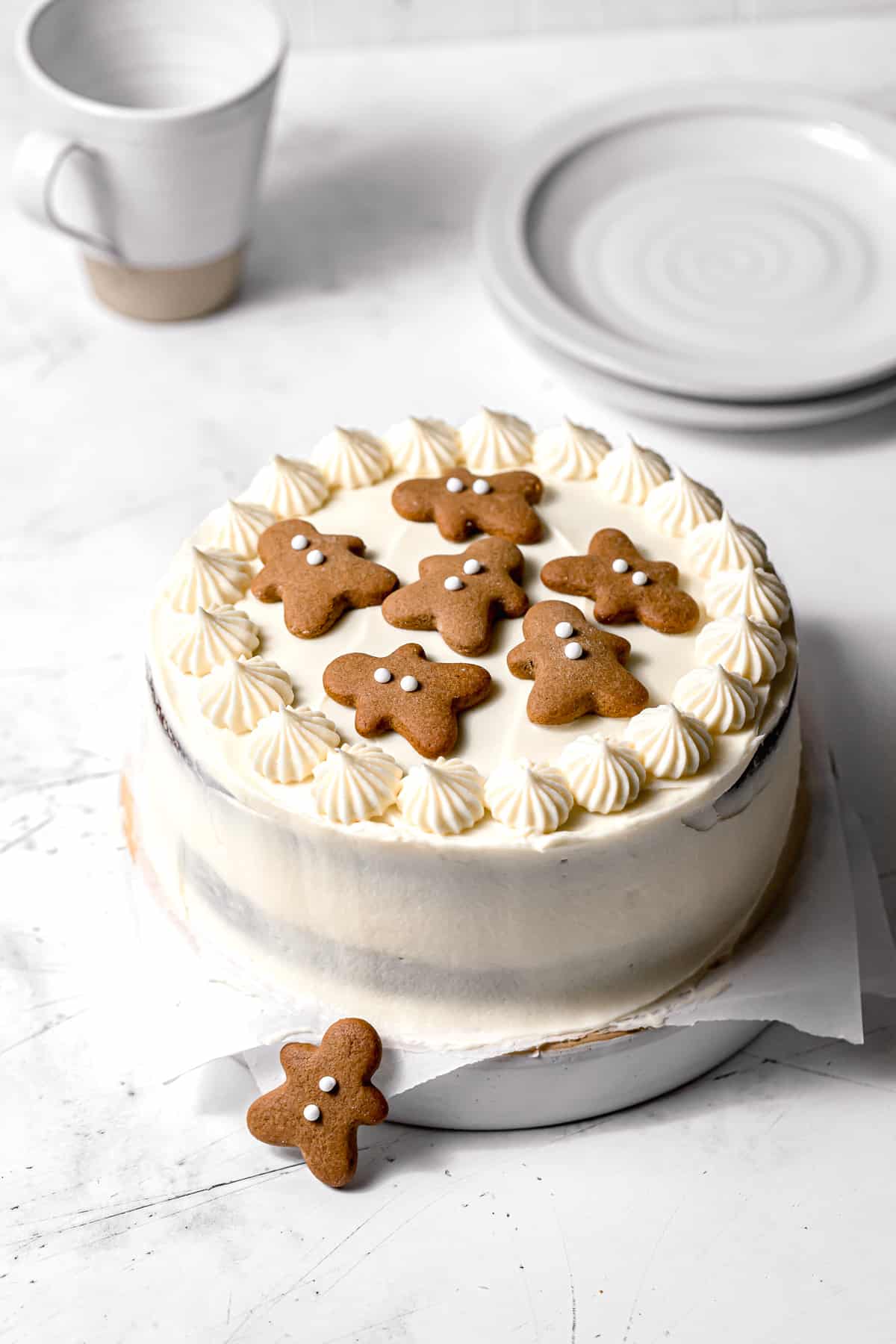 gingerbread cake with cream cheese frosting topped with gingerbread cookies