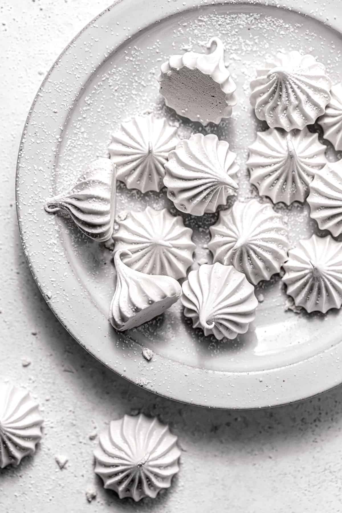 meringue cookies sprinkled with powdered sugar on white plate.