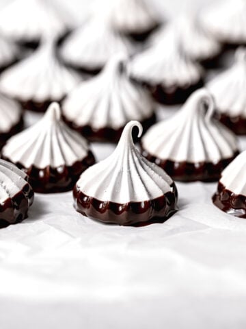 chocolate dipped meringue cookies on parchment paper
