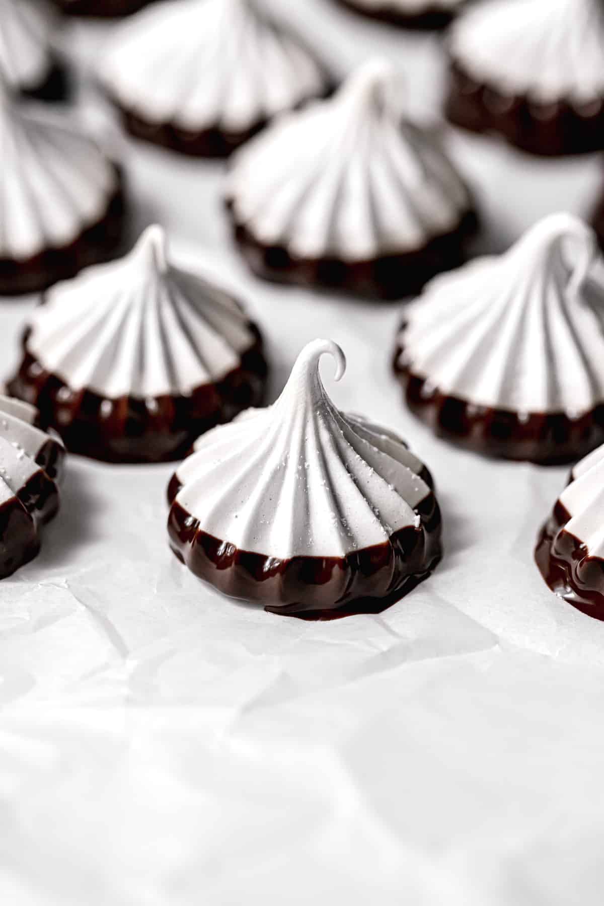 chocolate dipped meringue cookies on parchment paper.
