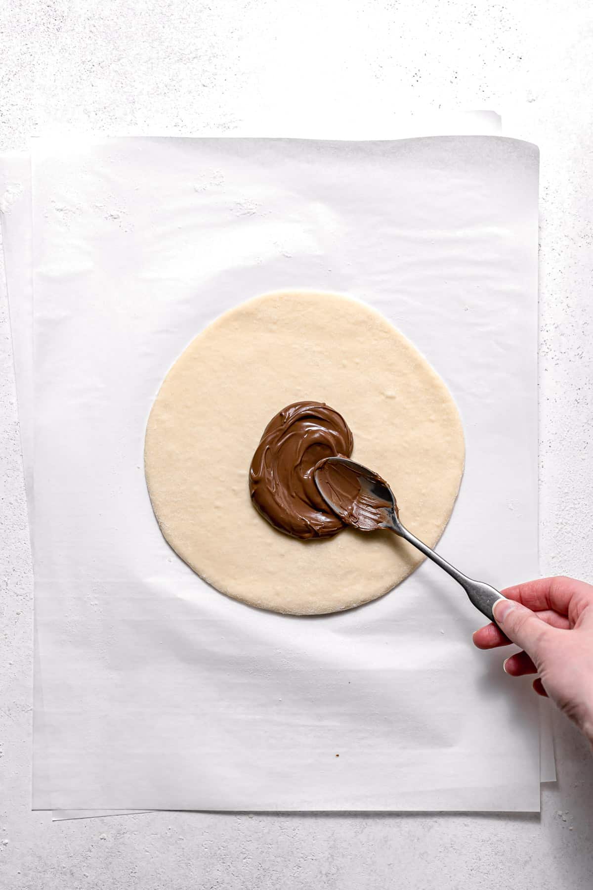 nutella being spread onto first dough layer