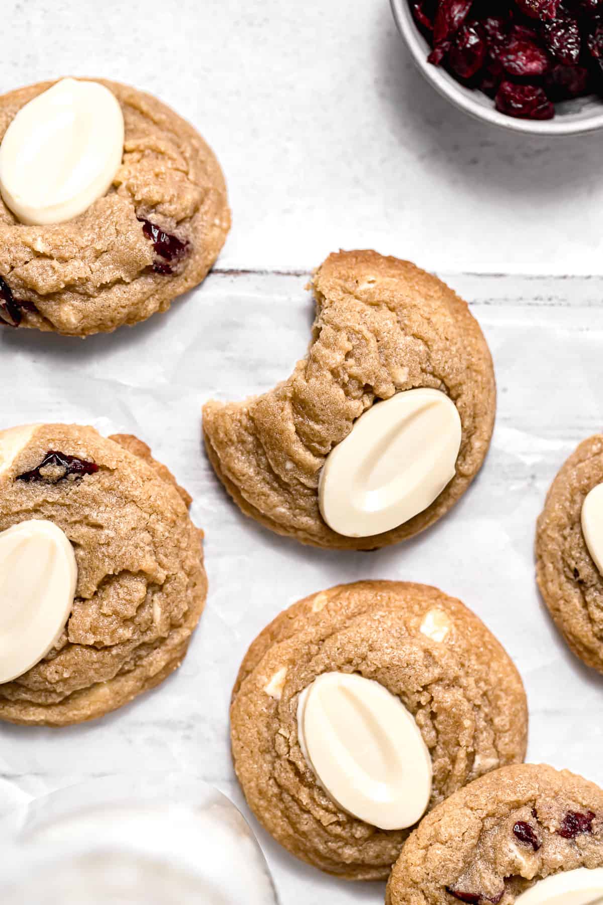 white chocolate cranberry cookies on parchment lined wooden board