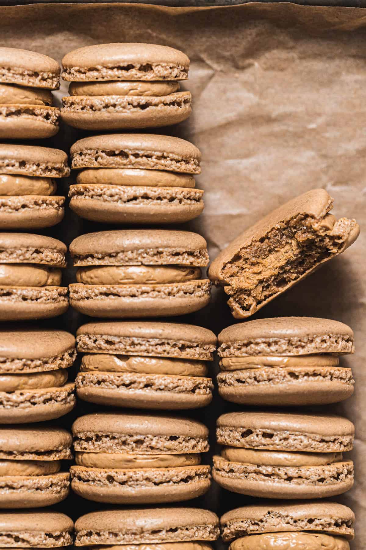 coffee macarons lined up on parchment paper.