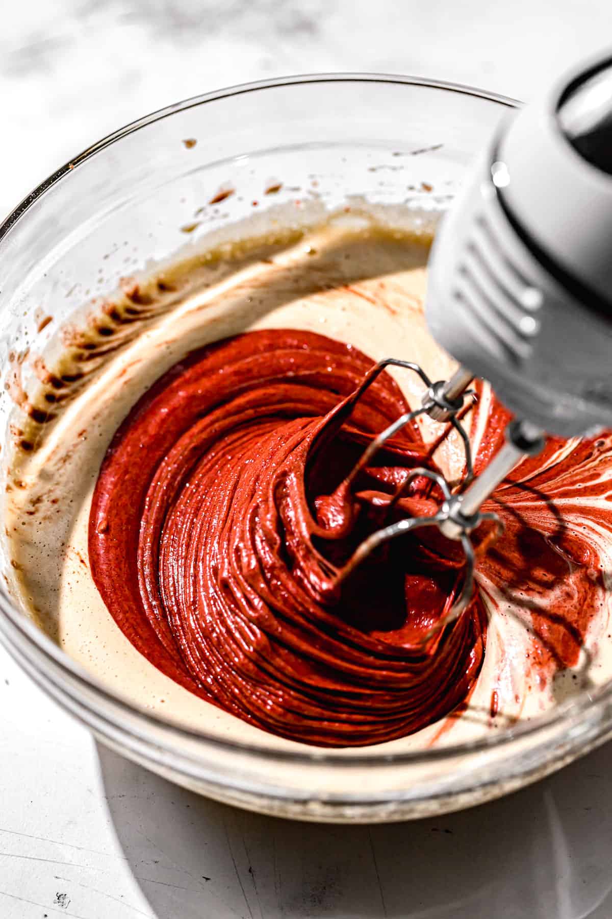 red chocolate mixture being mixed into the batter